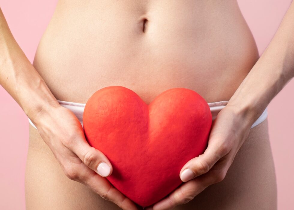 Heart shape held by woman near her reproductive system