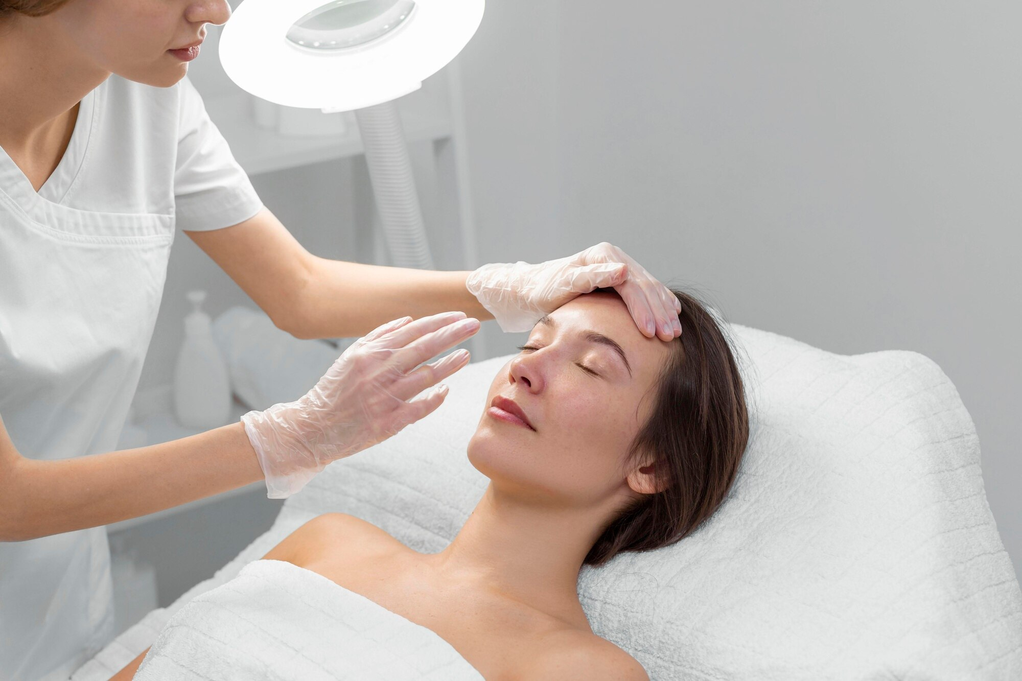 Beautician with female client at salon for face care routine