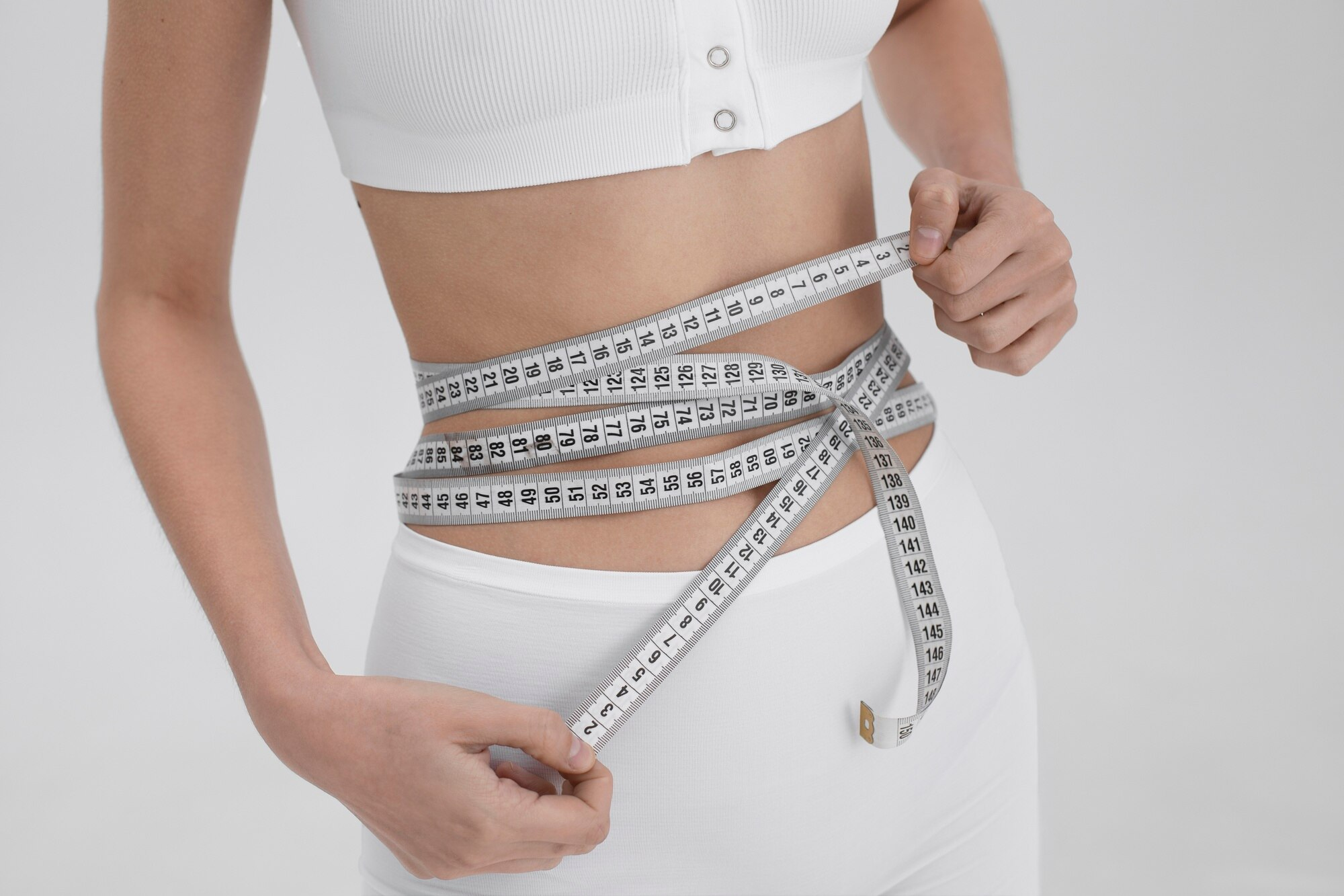 Young woman with an eating disorder using a tape measure